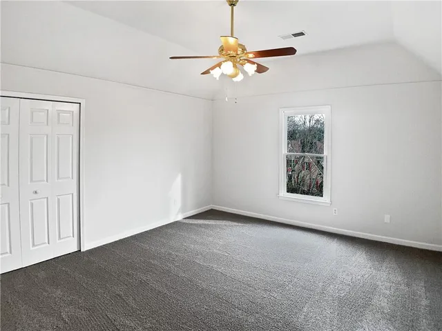 an empty room with windows and fan