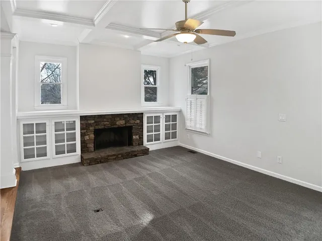 an empty room with windows and fireplace