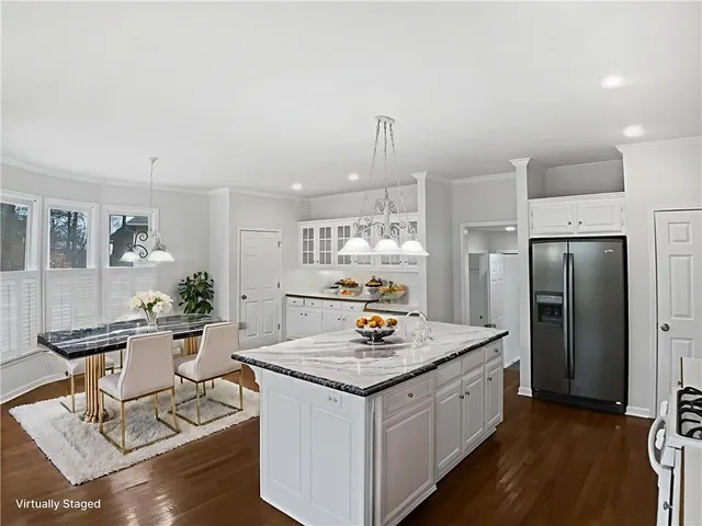 a kitchen with stainless steel appliances kitchen island granite countertop a refrigerator a stove and white cabinets with wooden floor