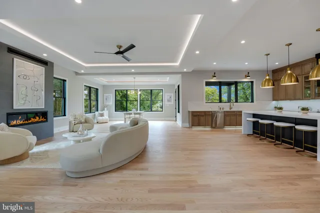 a living room with furniture kitchen area and a large window