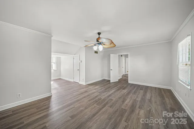 an empty room with wooden floor ceiling fan and windows