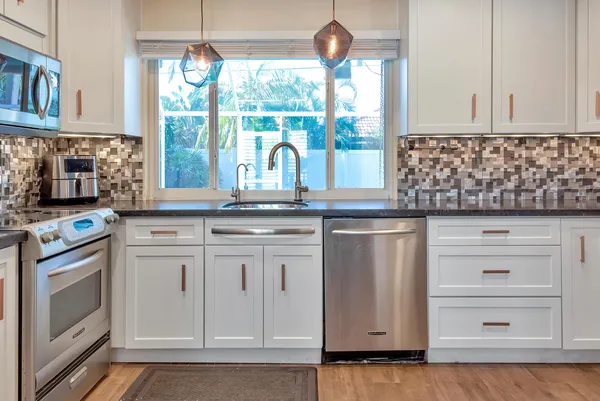 a kitchen with stainless steel appliances granite countertop a sink a stove and cabinets