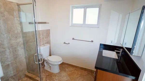a bathroom with a granite countertop toilet sink and mirror