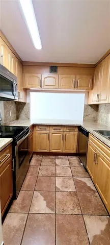 a large kitchen with granite countertop a stove a sink and a microwave