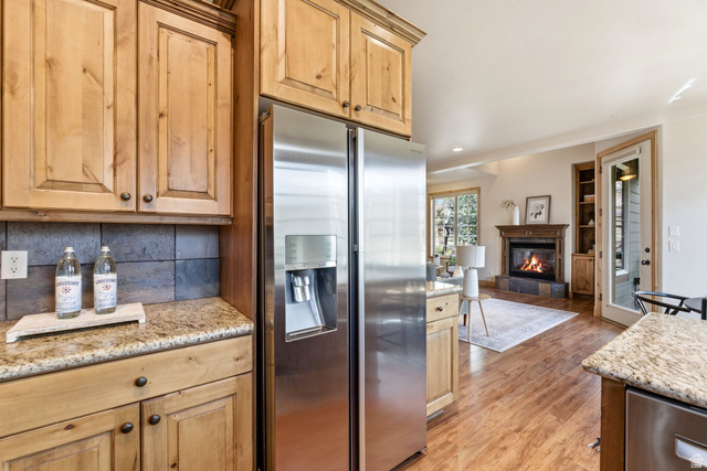 3026 Lower Saddleback Road Park City, UT 84098 - Photo 17 of 71 Kitchen featuring stainless steel appliances, light stone counters, a glass covered fireplace, light wood-style floors, and built in features