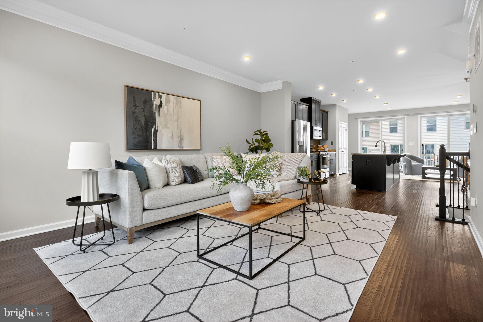 a living room with furniture a wooden floor and kitchen view