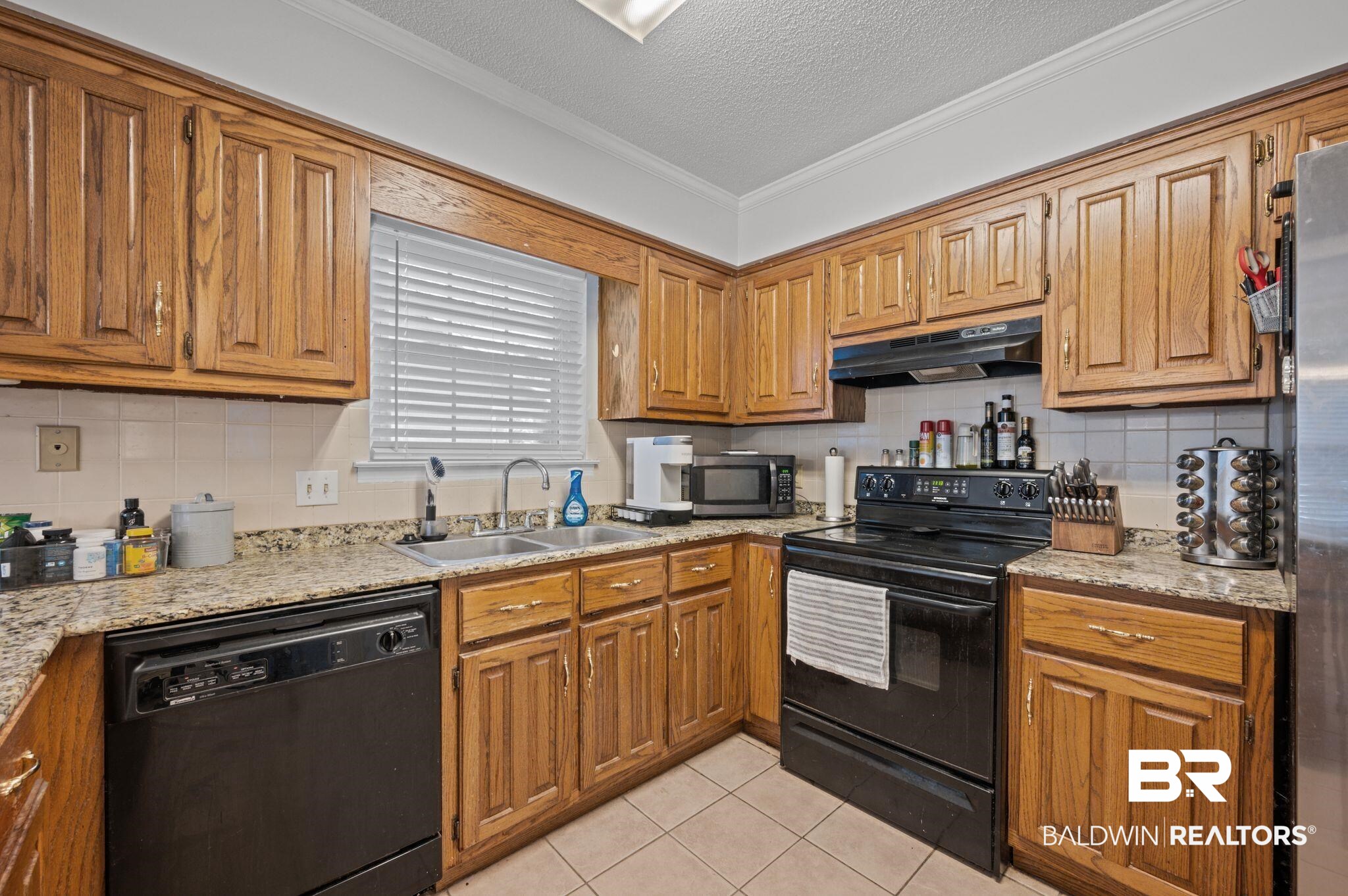 6705 Autumn Ridge Drive Mobile, AL 36695 - Photo 14 of 24 Kitchen featuring black appliances, crown molding, sink, a textured ceiling, and light tile patterned flooring