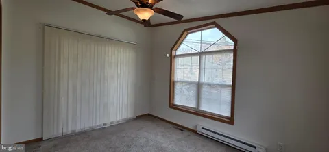 an empty room with windows and chandelier fan