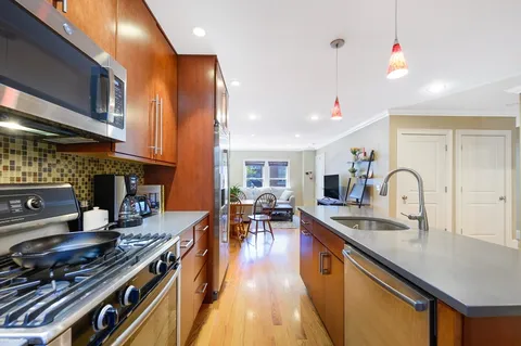 a kitchen with stainless steel appliances granite countertop a stove top oven a sink dishwasher a dining table and chairs with wooden floor