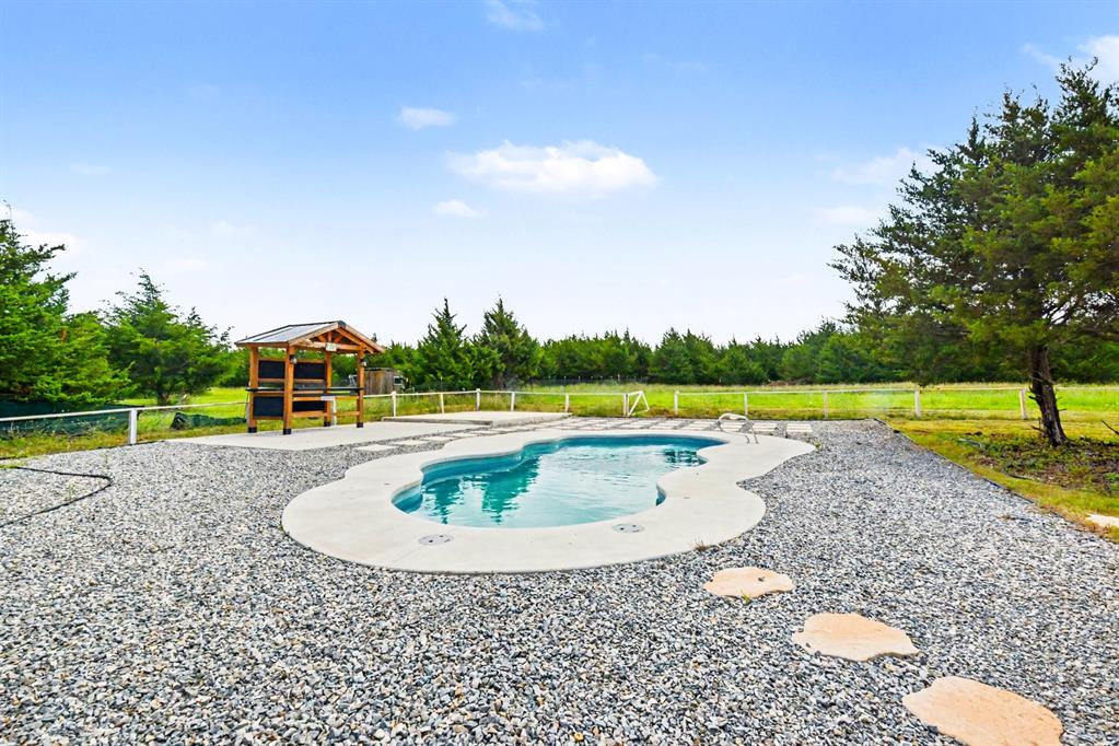 530 P R 491 Leonard, TX 75452 - Photo 30 of 35 Freeform swimming pool surrounded by a gravel patio with stepping stones