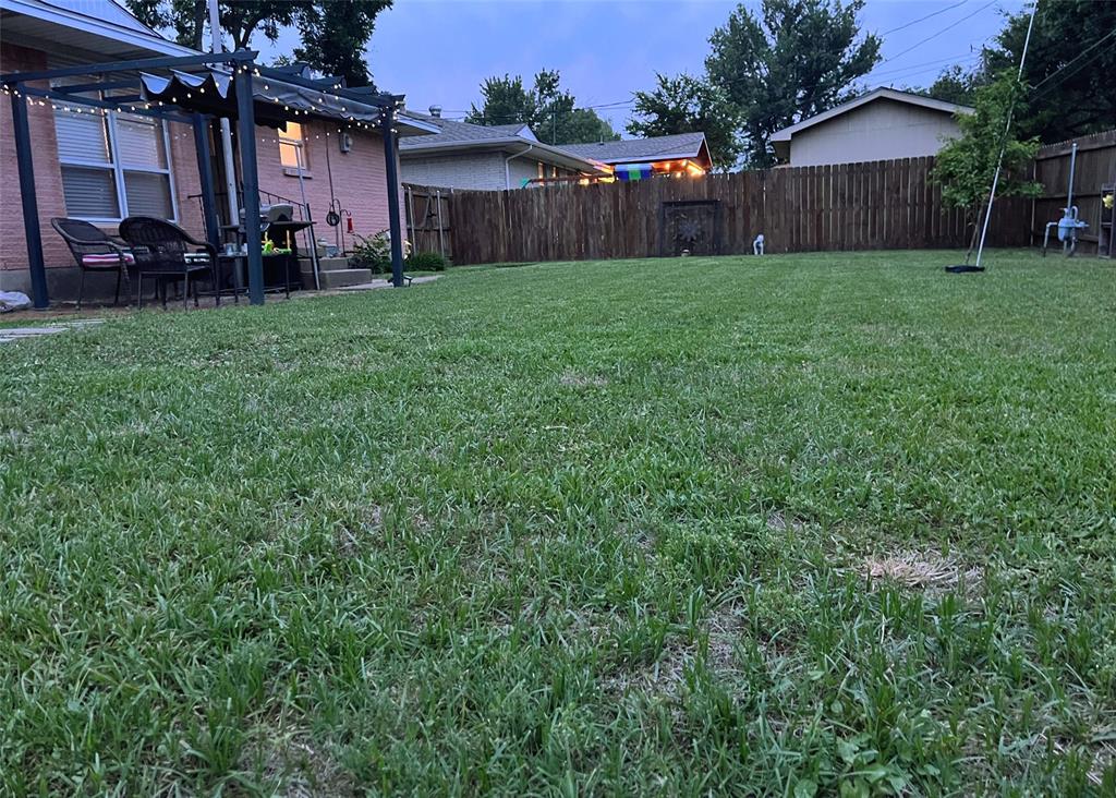 2602 Ridgecrest Drive Garland, TX 75041 - Photo 19 of 24 a view of a backyard with table and chairs and wooden fence