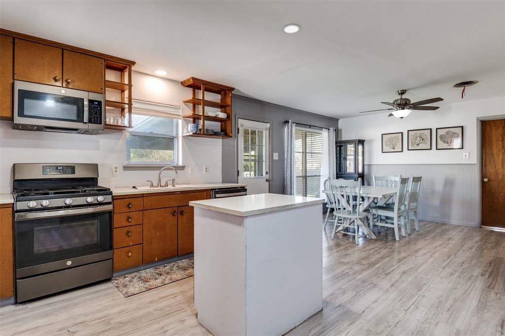 2602 Ridgecrest Drive Garland, TX 75041 - Photo 7 of 24 a kitchen with stainless steel appliances granite countertop a stove top oven a sink dishwasher a dining table and chairs with wooden floor