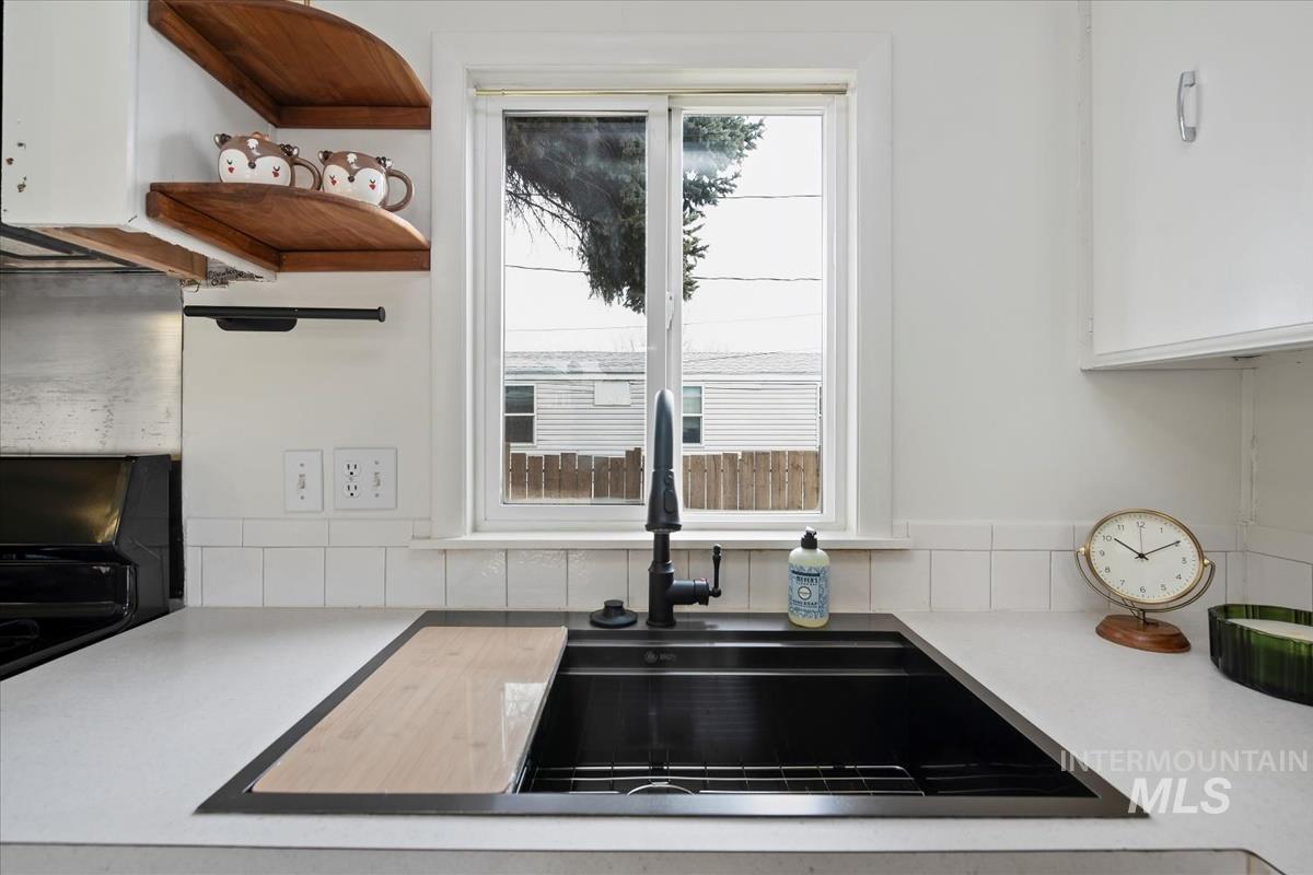 10167 Maymie Road Boise, ID 83714 - Photo 11 of 31 Kitchen view of light countertops, open shelves, white cabinets, and decorative backsplash