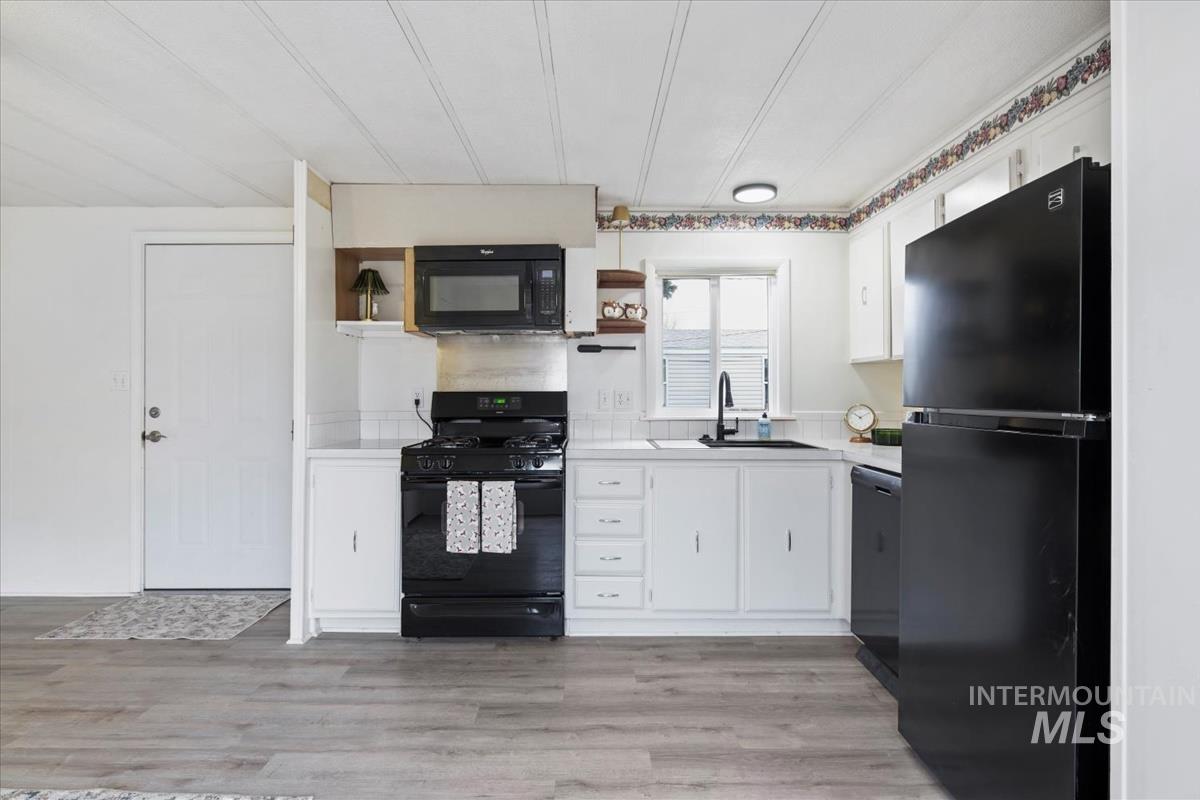 10167 Maymie Road Boise, ID 83714 - Photo 12 of 31 Kitchen featuring black appliances, white cabinetry, open shelves, and light countertops
