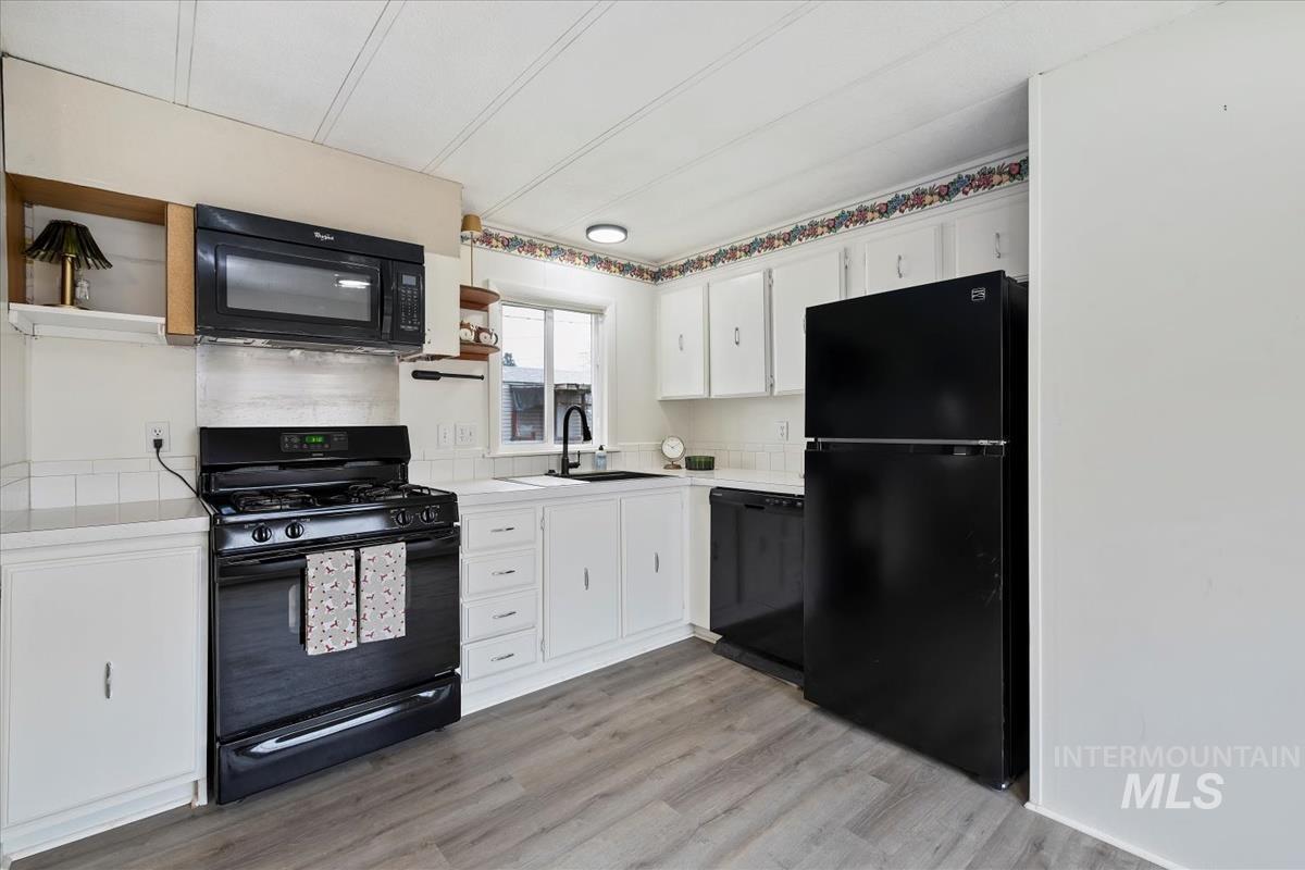 10167 Maymie Road Boise, ID 83714 - Photo 13 of 31 Kitchen featuring open shelves, white cabinetry, black appliances, and light wood-style flooring