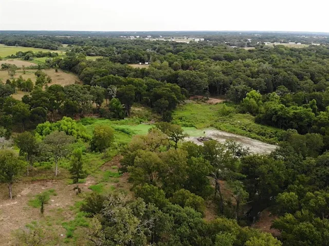 an aerial view of residential houses with outdoor space and trees