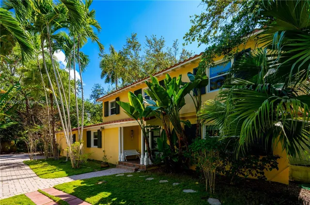 a view of swimming pool with lawn chairs and large trees