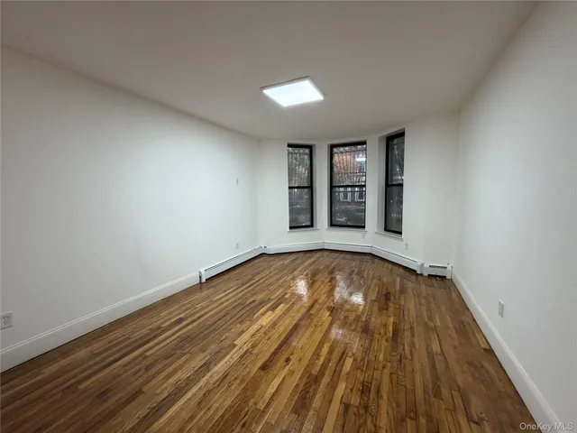 a view of an empty room with wooden floor and window