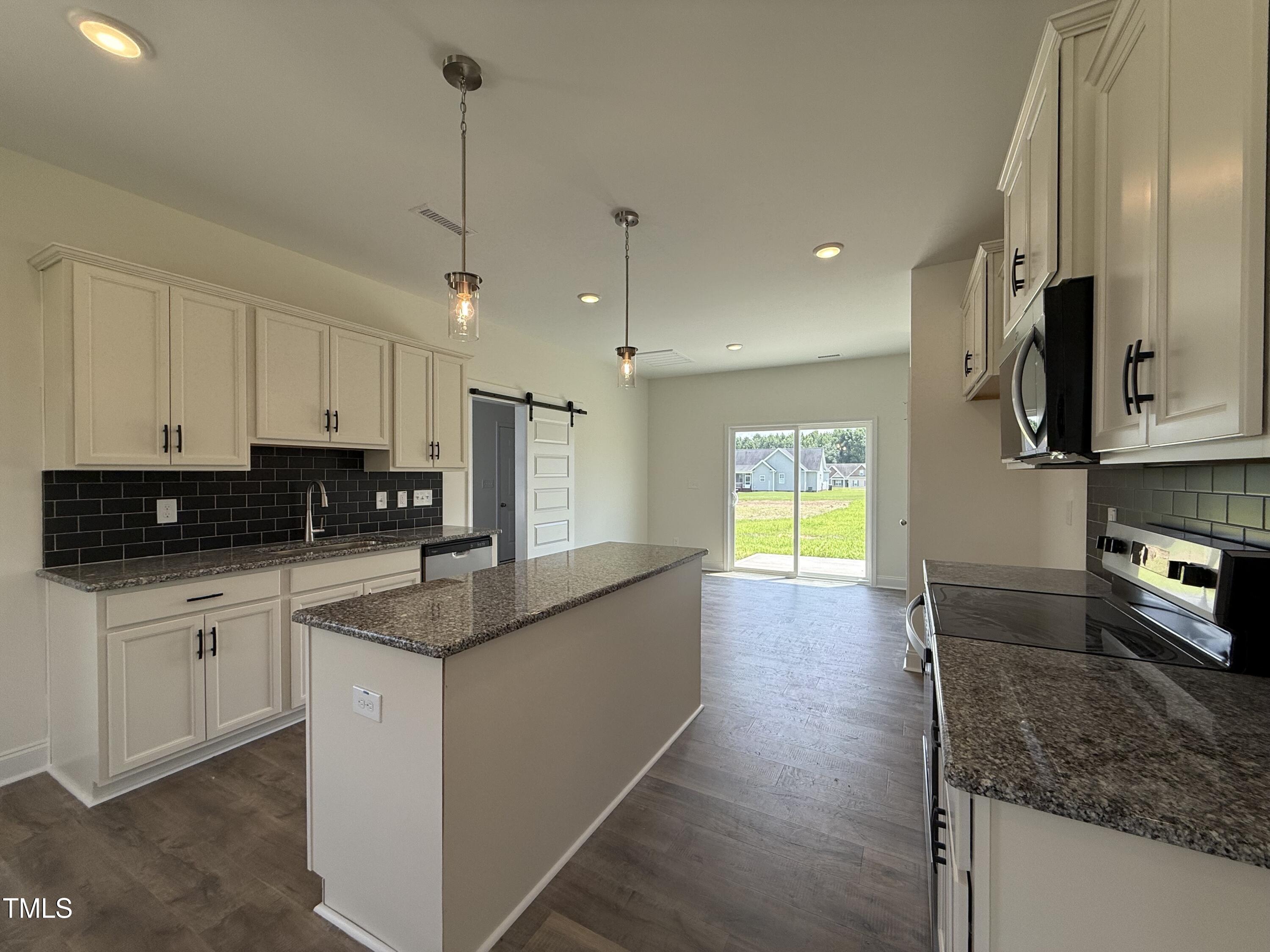 432 Springtooth Drive Zebulon, NC 27597 - Photo 3 of 15 a kitchen with stainless steel appliances granite countertop a sink a stove top oven a counter space and cabinets