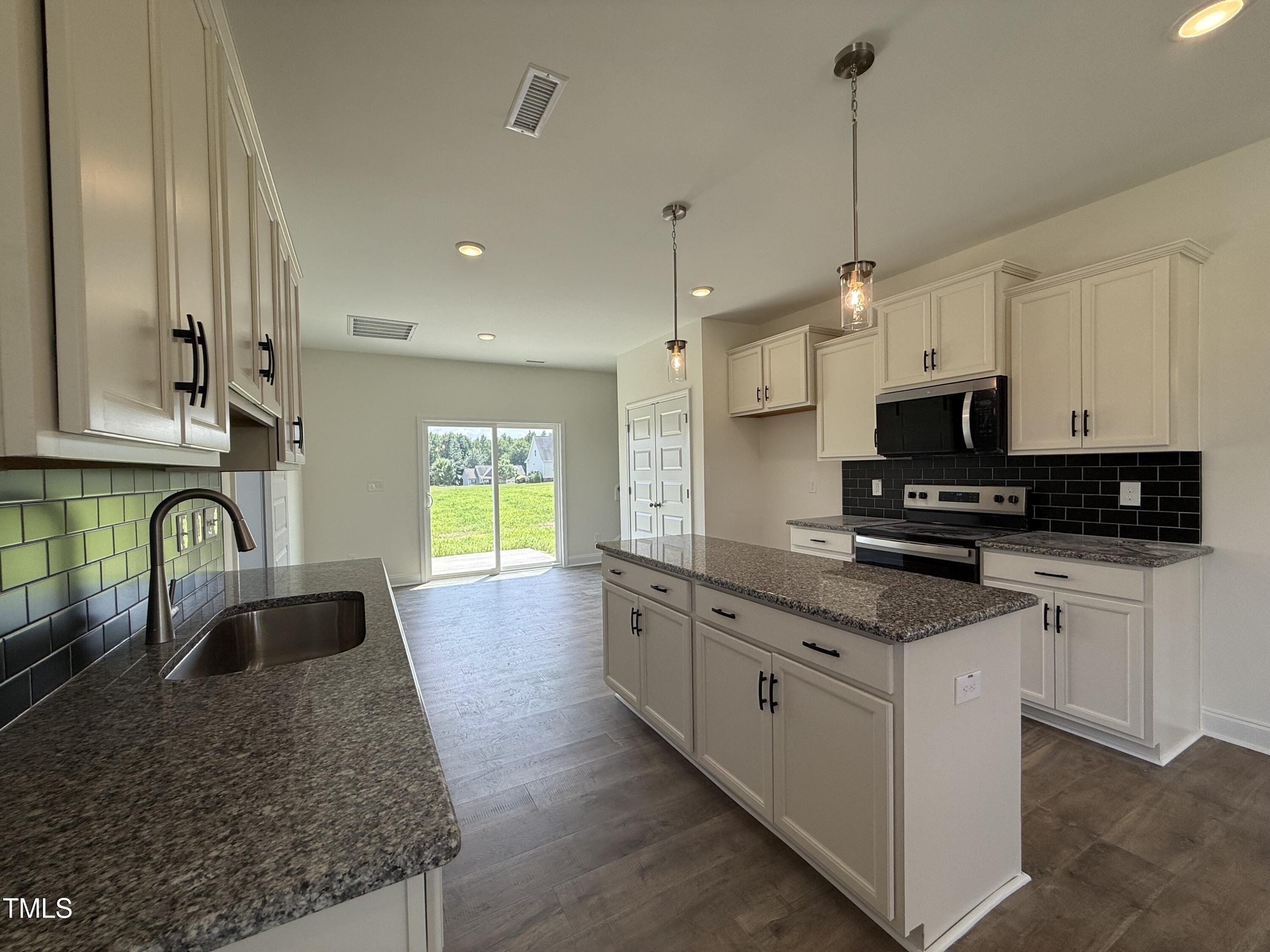 432 Springtooth Drive Zebulon, NC 27597 - Photo 4 of 15 a kitchen with stainless steel appliances granite countertop a sink a stove a microwave a counter space and cabinets