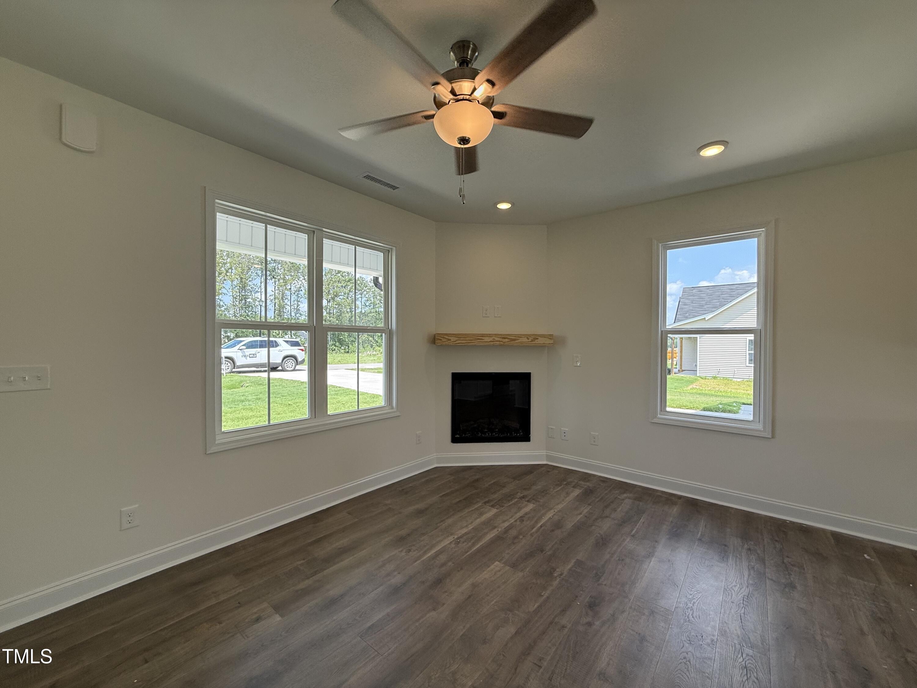 432 Springtooth Drive Zebulon, NC 27597 - Photo 5 of 15 an empty room with wooden floor chandelier fan and windows