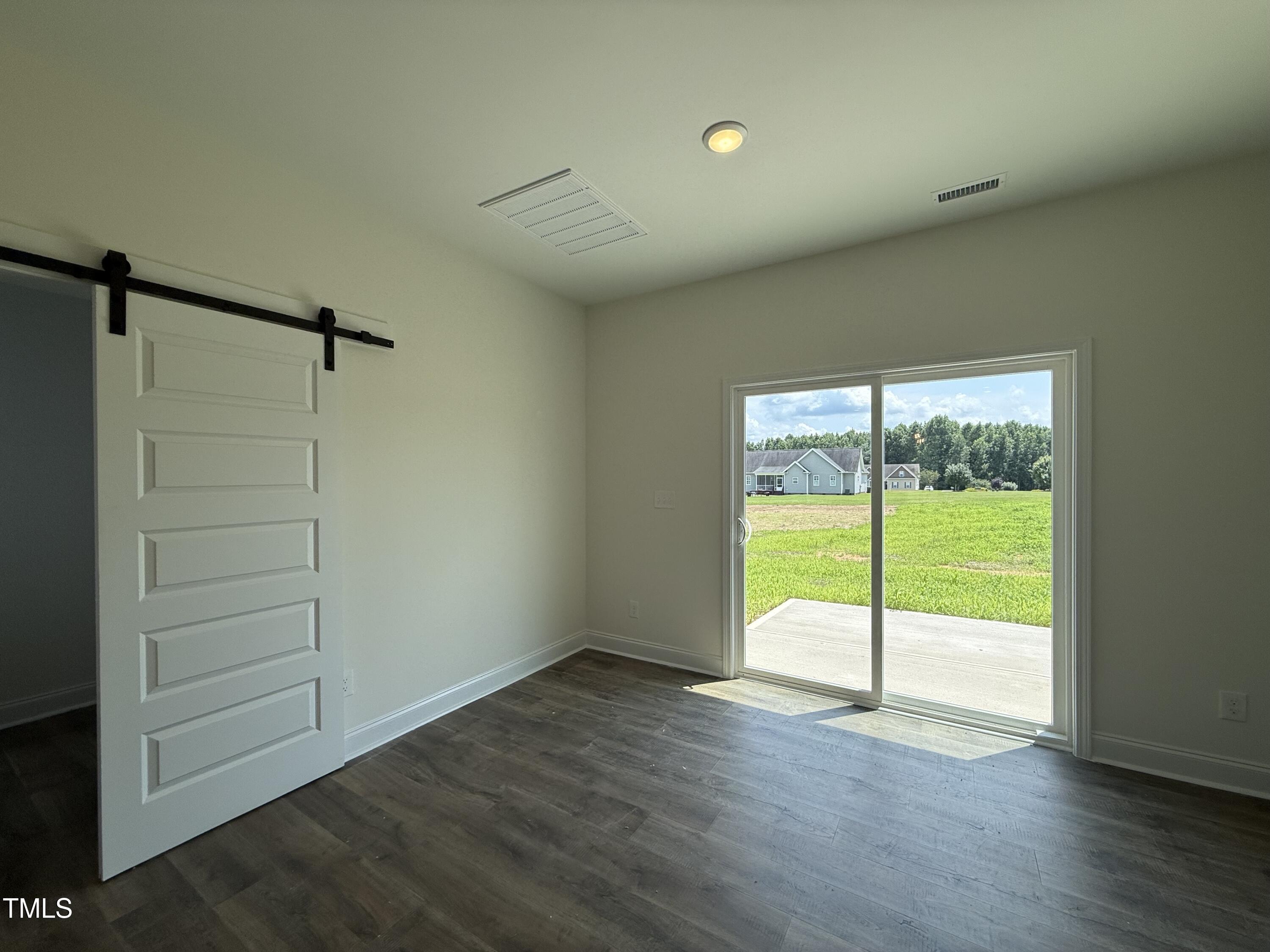 432 Springtooth Drive Zebulon, NC 27597 - Photo 6 of 15 an empty room with wooden floor and door