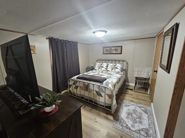 a bedroom with a bed and a table with wooden floor