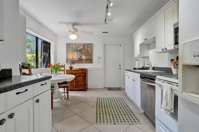 a kitchen with granite countertop white cabinets and refrigerator