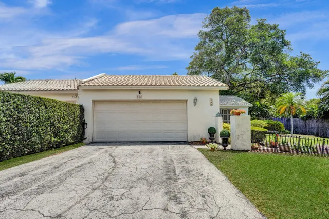 a front view of a house with a yard and a tree