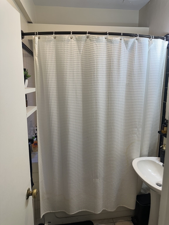 69 A Strathmore Road, Unit 69A Boston, MA 02135 - Photo 11 of 12 a bathroom with a shower curtain and sink