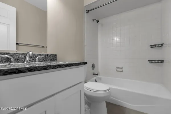 a bathroom with a granite countertop sink a toilet and bathtub
