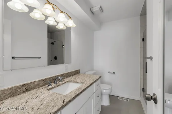 a bathroom with a granite countertop sink a toilet and mirror