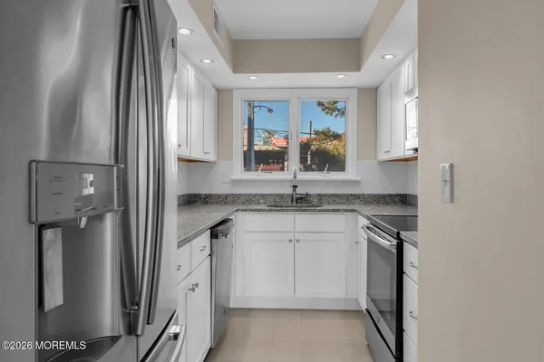 a kitchen with stainless steel appliances granite countertop a sink and a refrigerator