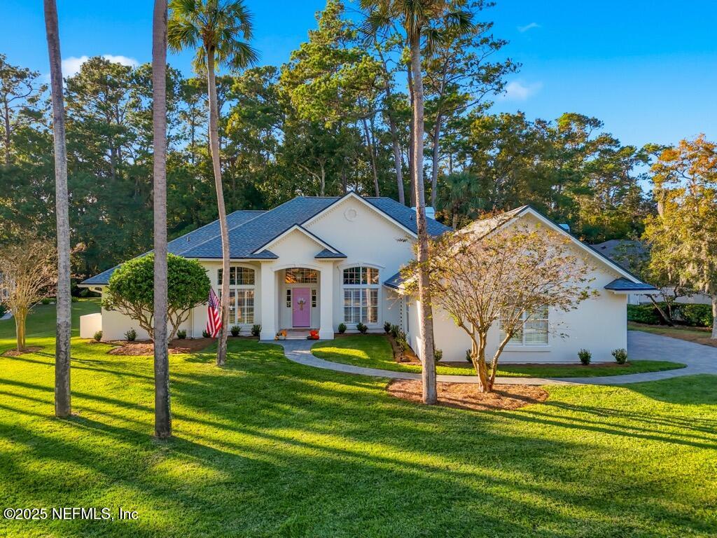 a view of a house with a big yard and potted plants and large trees