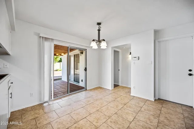 a spacious bedroom with a chandelier and glass door