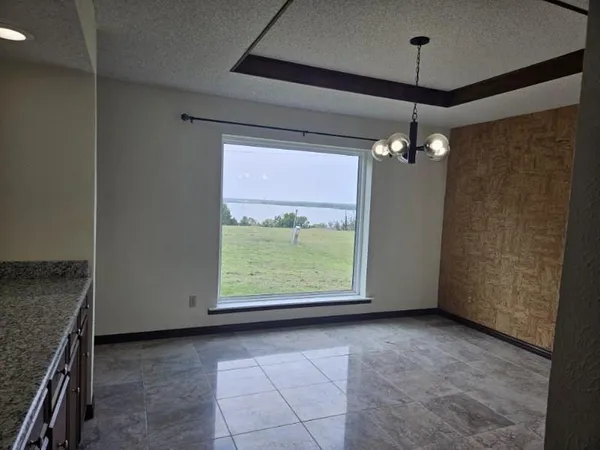 an empty room with chandelier fan and windows