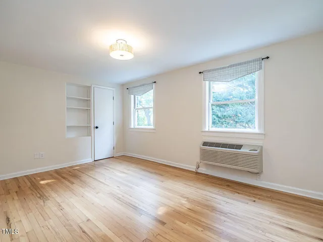 a view of an empty room with a window and wooden floor