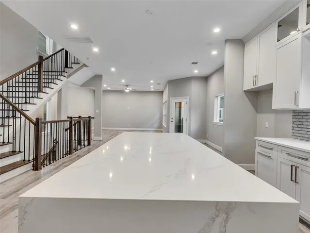 a large white kitchen with wooden floor and a sink