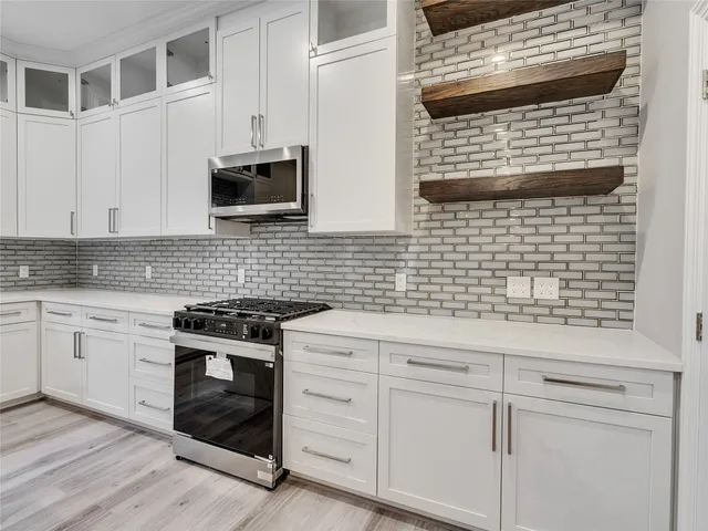a kitchen with stainless steel appliances kitchen island granite countertop a stove top oven a sink dishwasher a microwave oven with cabinets and wooden floor