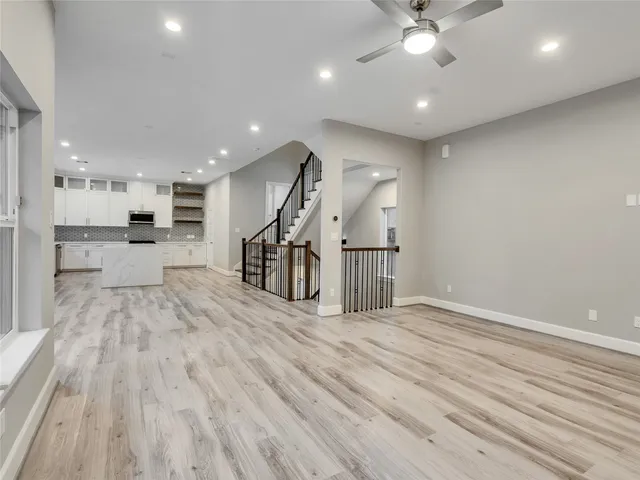 a view of a big room with wooden floor a ceiling fan and windows