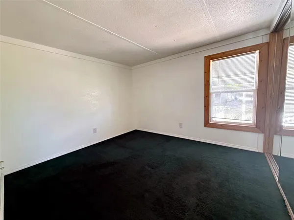 a view of an empty room with wooden floor and windows