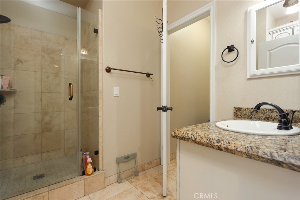 42561 25th Street West Lancaster, CA 93536 - Photo 29 of 41 a bathroom with a granite countertop sink a mirror and a shower