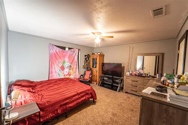 a bedroom with a bed flat screen tv and windows