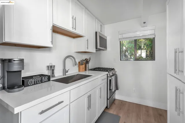 a kitchen with stainless steel appliances granite countertop a sink stove and white cabinets with wooden floor