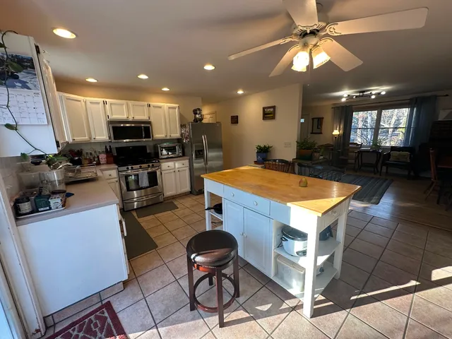 a kitchen with stainless steel appliances kitchen island granite countertop a sink cabinets and wooden floor