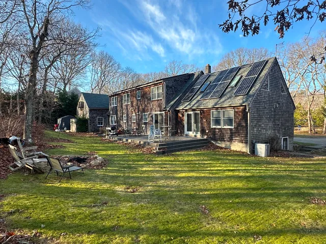 a view of a house with a big yard potted plants and large tree