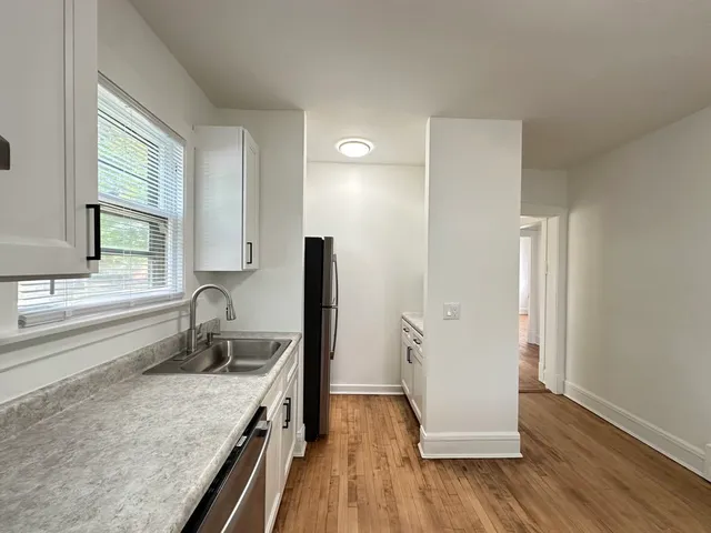 a kitchen with a sink a refrigerator and wooden floor