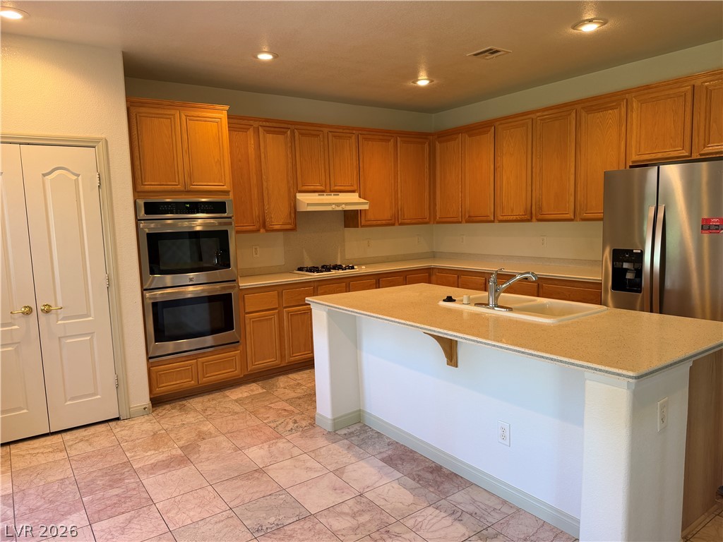 141 Rancho Maria Street Las Vegas, NV 89148 - Photo 9 of 30 Ample wooden cabinetry and a central island highlight this spacious tiled kitchen area.