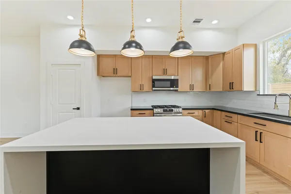 a kitchen with stainless steel appliances a sink a stove a refrigerator and white cabinets
