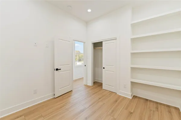 a view of an empty room with wooden floor and closet